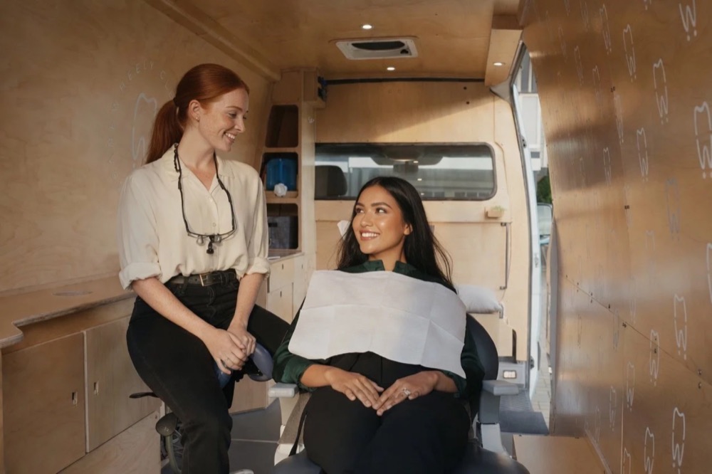 A licensed dental hygienist chatting with a patient inside the Wheely Clean mobile clinic